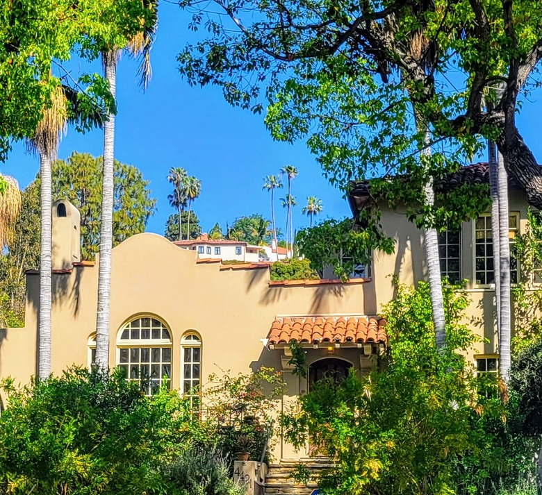 Beige colored two story home with red tile roof