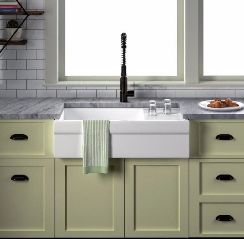 Apron front white sink with light green cabinets
