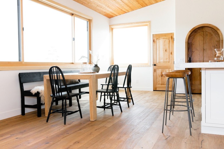 An open interior space a large dining table on one side and a white kitchen island on the other side. At the table