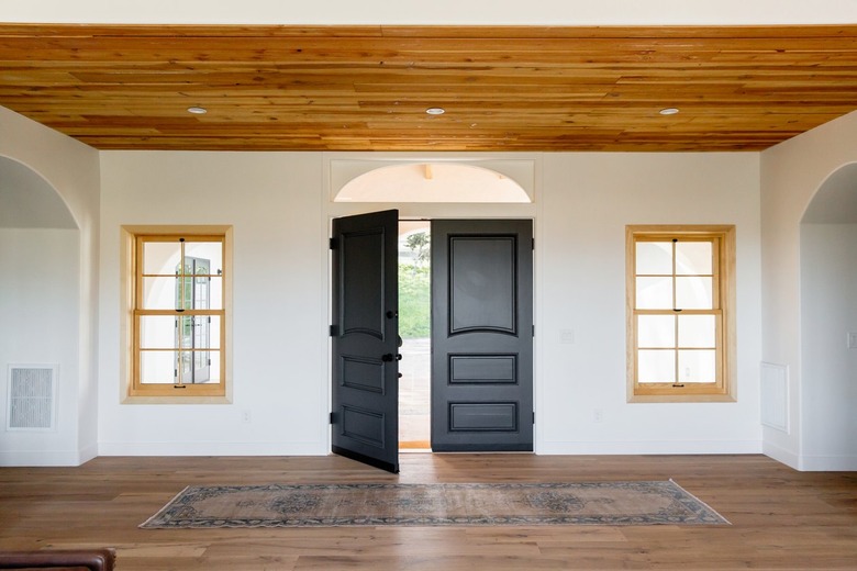 An entry hall of a Spanish-style home with double dark wood doors