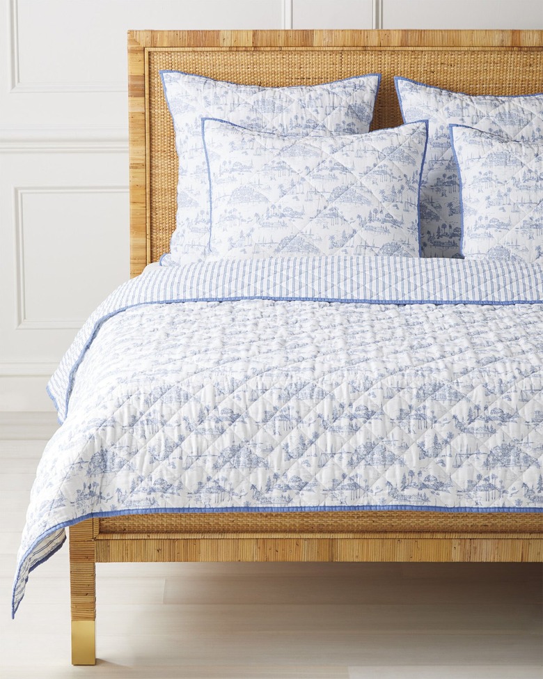 Blue and white toile cottagecore bedding on a light wooden bed