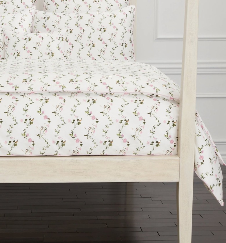 White cottagecore bedding with small pink flowers on a cream poster bed