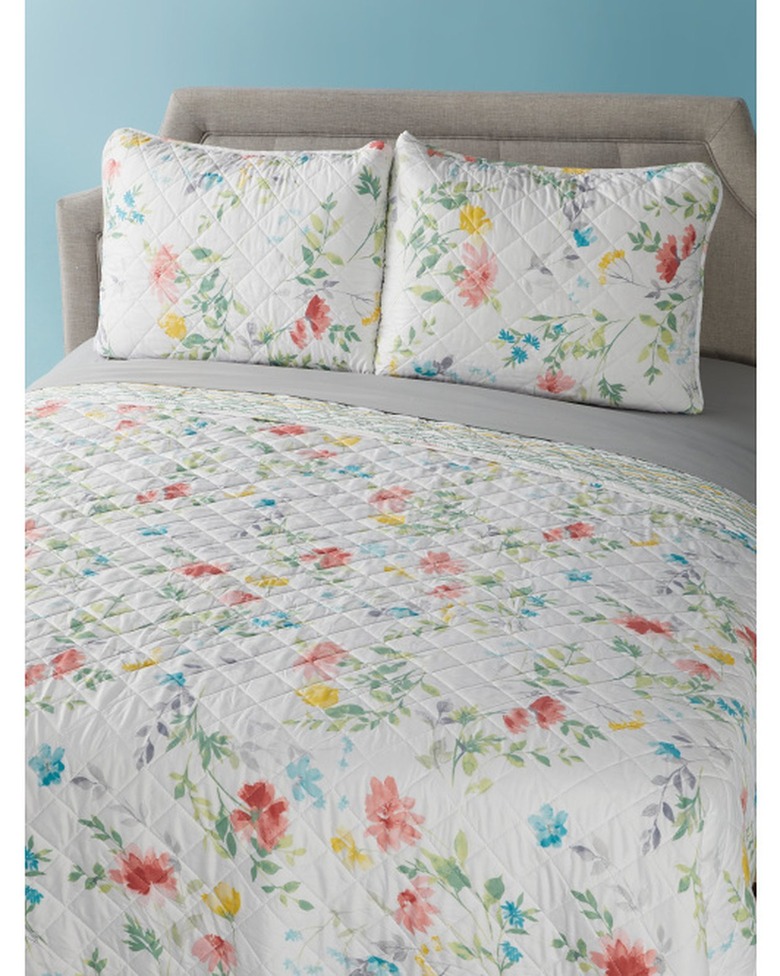 bed with white quilt with colorful flowers