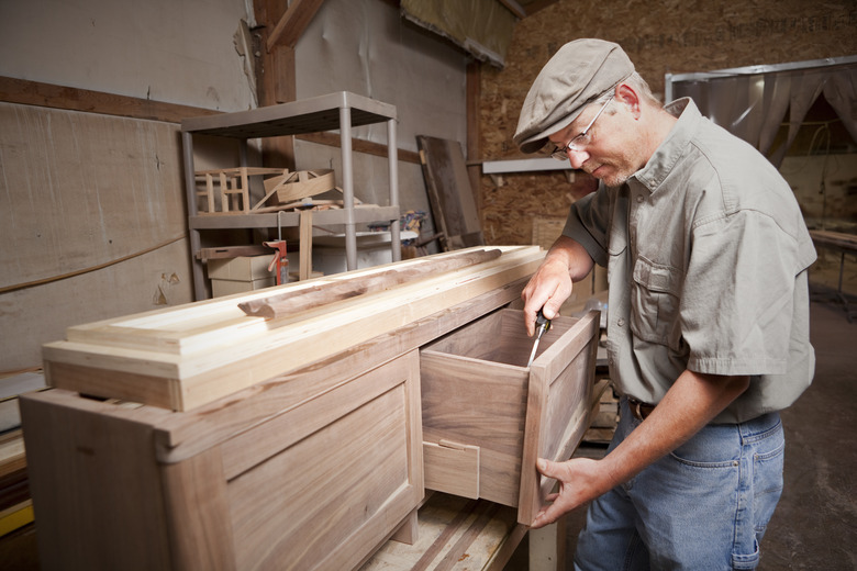 Carpenter uses chisel tool on cabinet drawer