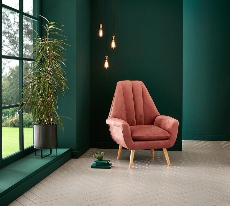 room with deep green walls and pink chair