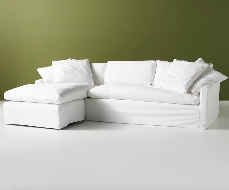 Anthropologie Upcycled Wells Slipcover Reversible Sectional in white against a green wall