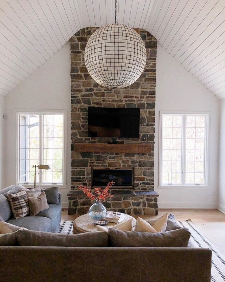 White living room with stone fireplace and shiplap ceiling