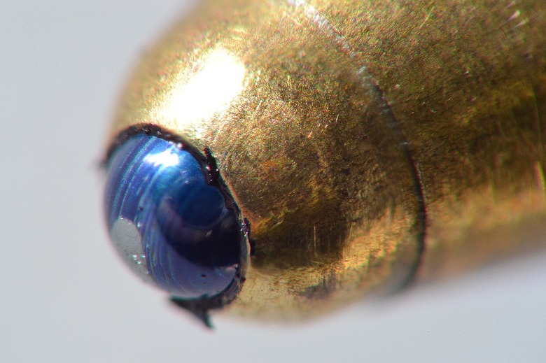 The magnified tip of a ballpoint pen showing the ball covered with ink