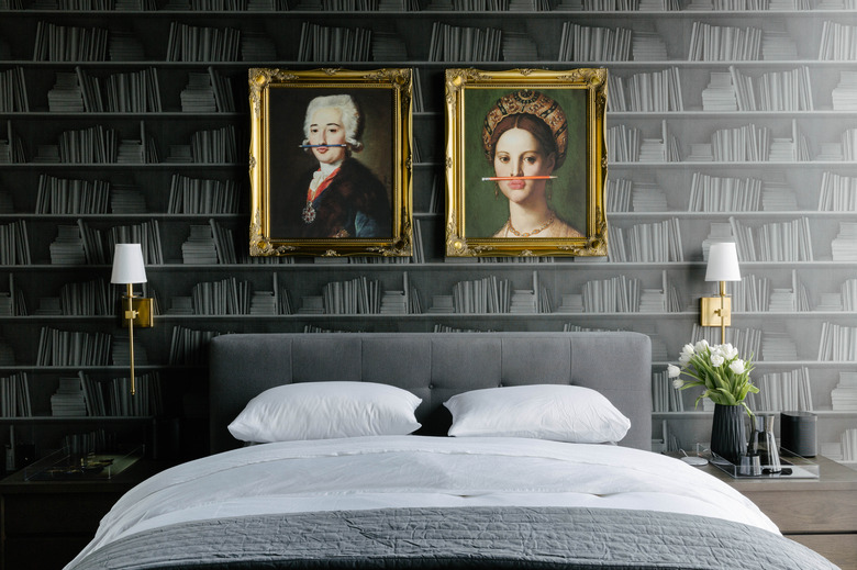 black bedroom with gold accents and shelf-lined wallpaper