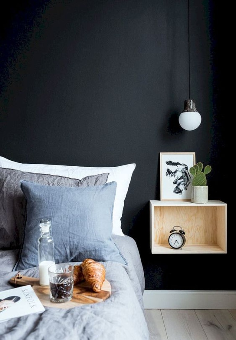 bedroom with black walls and floating nightstand