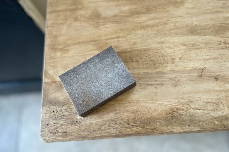 Sanding the wood table with a sanding block