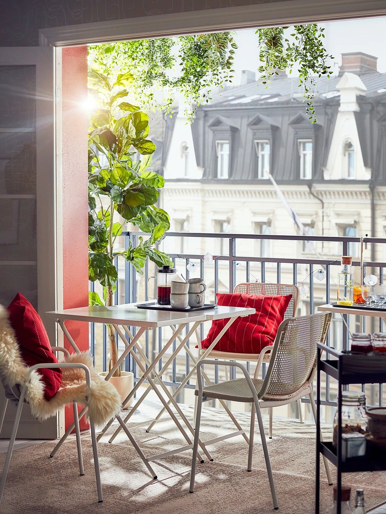 table with chairs and red pillows near large window with building in the background