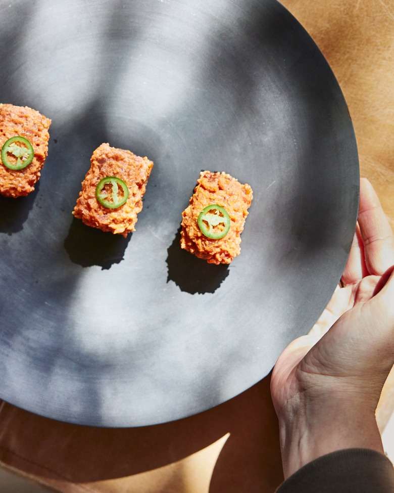 Three pieces of plant-based sushi on a circular black plate.