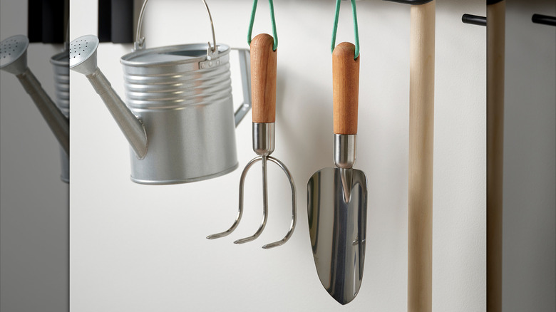 A pair of gardening hand tools hanging on a garage wall