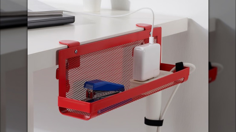 Computer cords and a small blue stapler are contained in a red FÖRSÄSONG Cable management tray