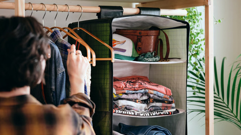 A person arranges clothes on hangars next to the KOMPISHÄNG Hanging storage find from IKEA