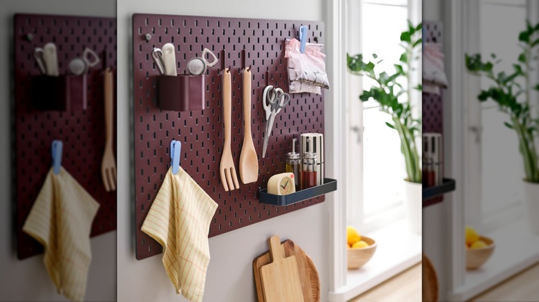A variety of kitchen items hang on a burgundy SKÅDIS 7-piece accessories set from IKEA
