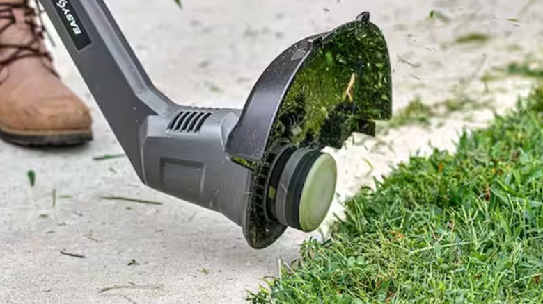 Person using Ryobi string trimmer to edge lawn