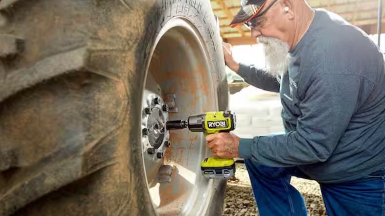 Man removing a tractor's tire lugs with a Ryobi impact wrench