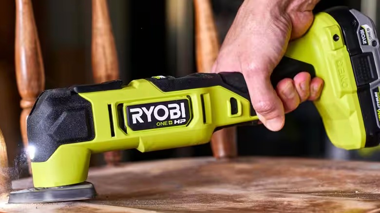 Person using Ryobi oscillating tool to cut chair back