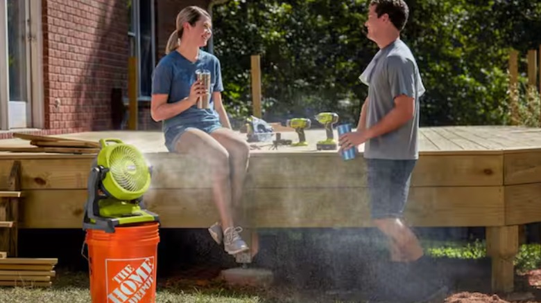 Two people lounging on deck while being cooled by Ryobi misting fan