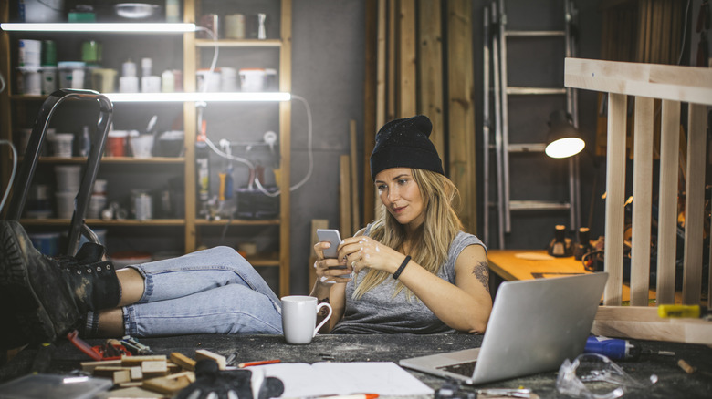 Woman in workshop surrounded by tools making an order on her phone