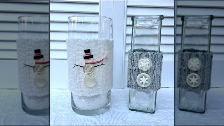 Two glass candle holders wrapped in vintage swear strips with decorative winter-themed buttons