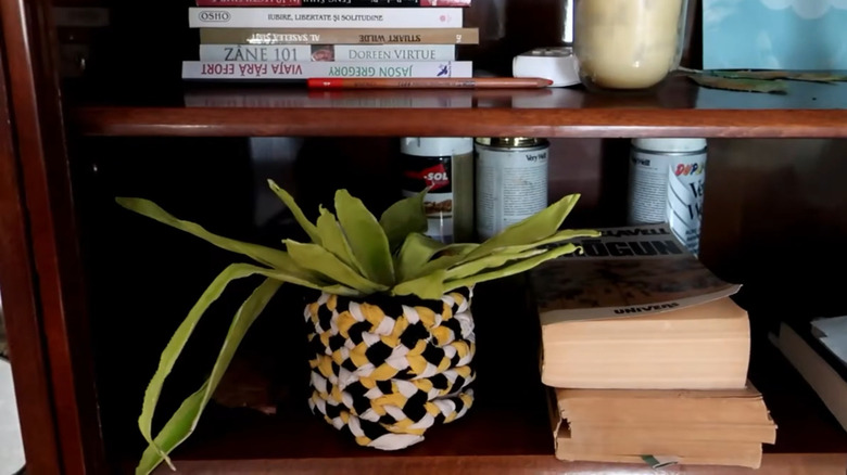 A plastic planter and fake plant made from strips of old clothes