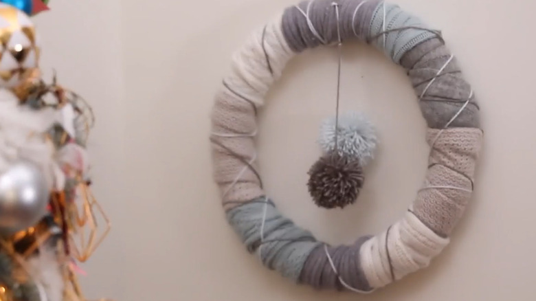 A gray and tan wreath with pom poms in the center