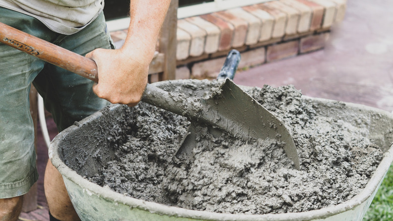 A person mixes concrete in a wheelbarrow