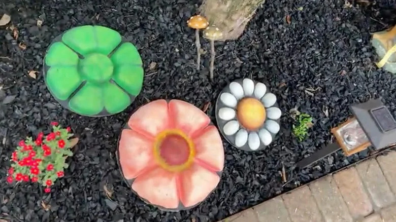 Three colorful floral stepping stones are in a mulched bed