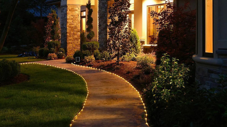 a path to the porch of a house lit with warm solar rope lights