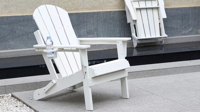 Two white Adirondack chairs sit on a gray patio