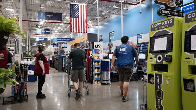 People walk through the aisles of Lowe's under an American flag