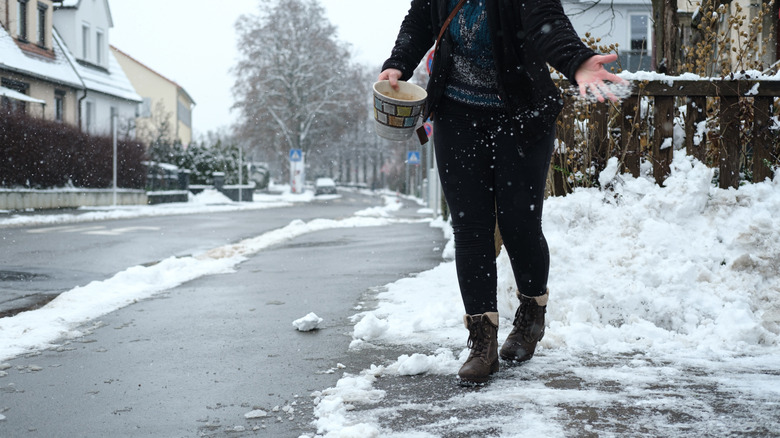 Woman spreading ice melt on slippery sidewalk