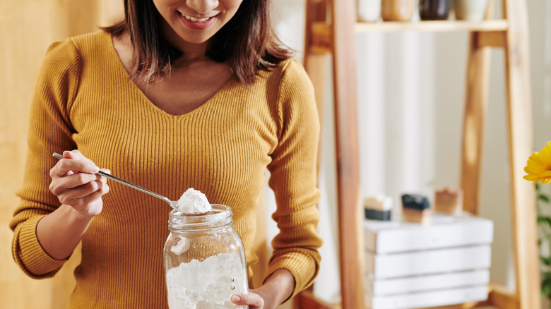 Smiling woman spooning baking soda out of a jar