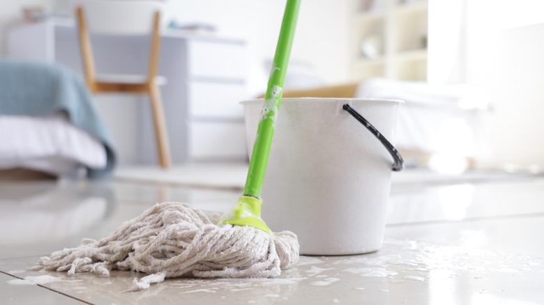 Mop and bucket on white tile floor