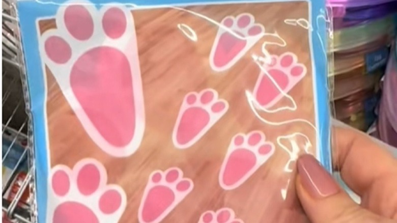 A woman holds a package of pink bunny footprint stickers in Dollar Tree.