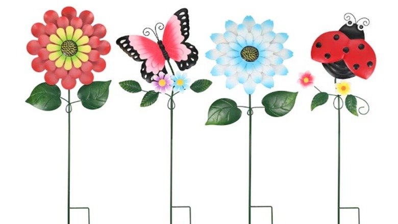 Four metal garden stakes topped with colorful icons including flowers, butterfly, and ladybug.