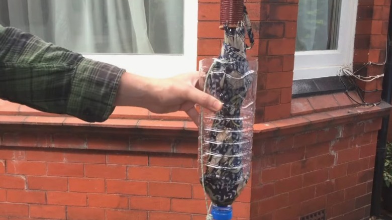 Person holding DIY umbrella holder made out of large water bottle