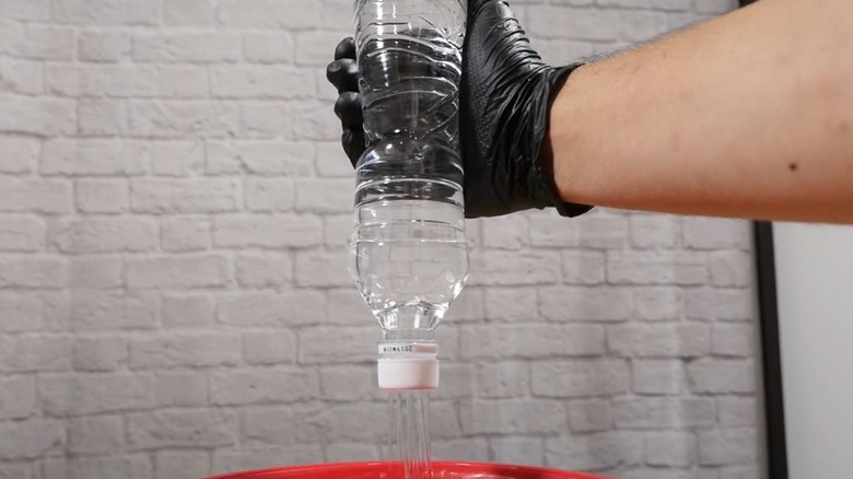Person squeezing water bottle turned into DIY shower