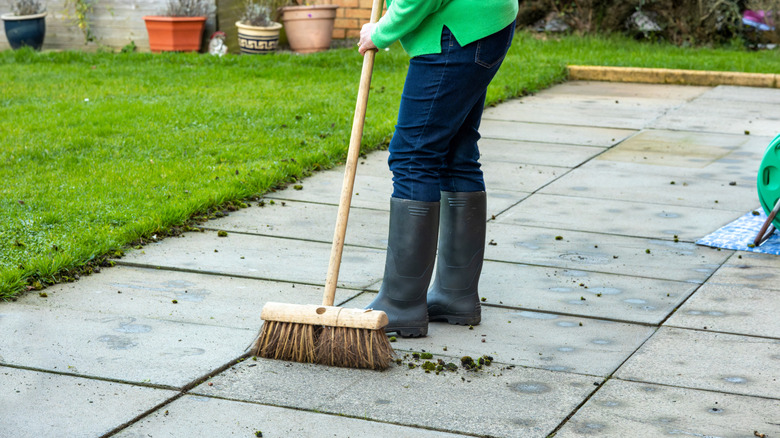 Using a brush-style broom on a concrete patio