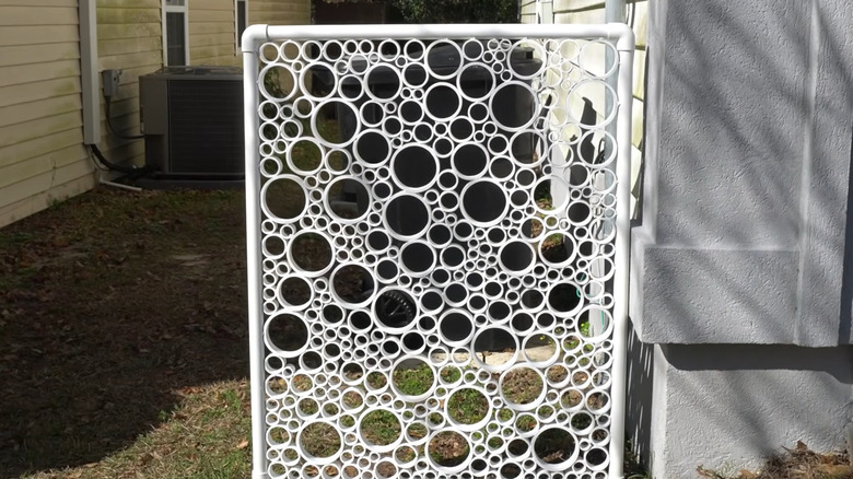 Privacy panel made from white PVC pipes attached to the side of the house