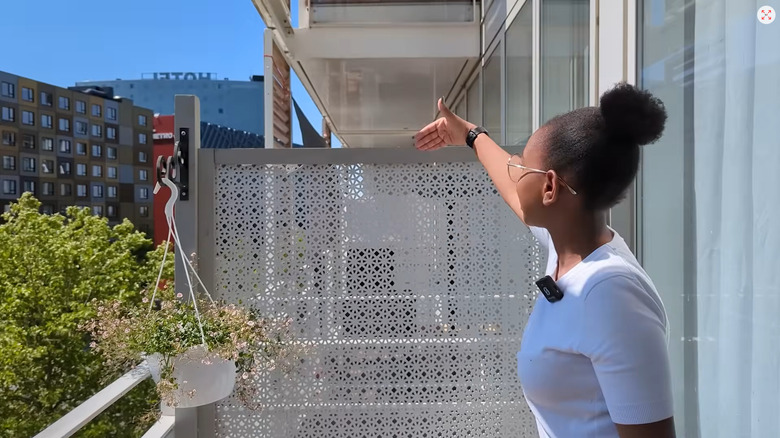 Person standing on a balcony showing a privacy screen made from flooring