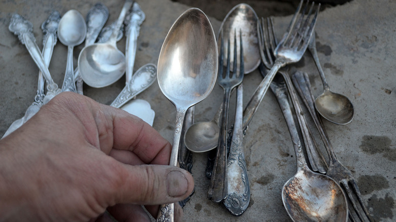 a man cleans rusted silverware