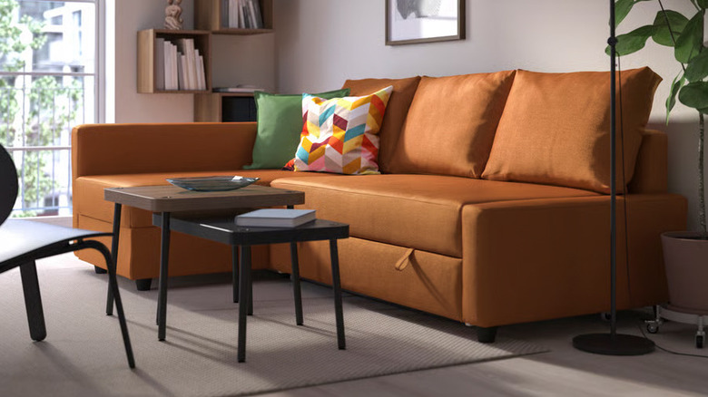 Colorful pillows sit in the corner of a burnt orange FRIHETEN Sleeper sectional from IKEA