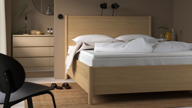 A modern brown bed frame holds a VALEVÅG Mattress and mattress pad in a neutral bedroom