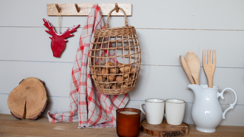 woven mini basket holding walnuts hanging from a peg rail mounted to the wall in a kitchen