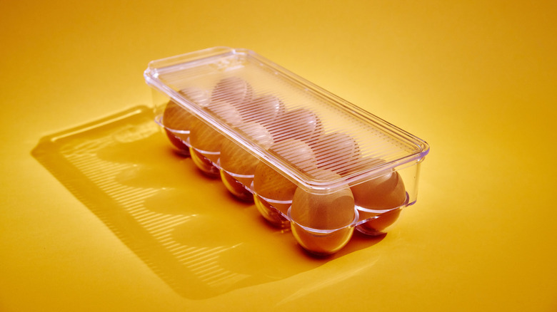 Eggs in a plastic egg container on a yellow background.