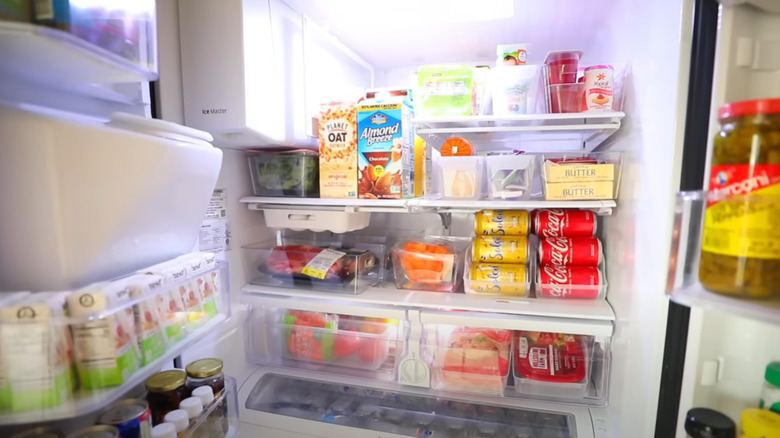 An open fridge with food and drinks organized into acrylic bins.